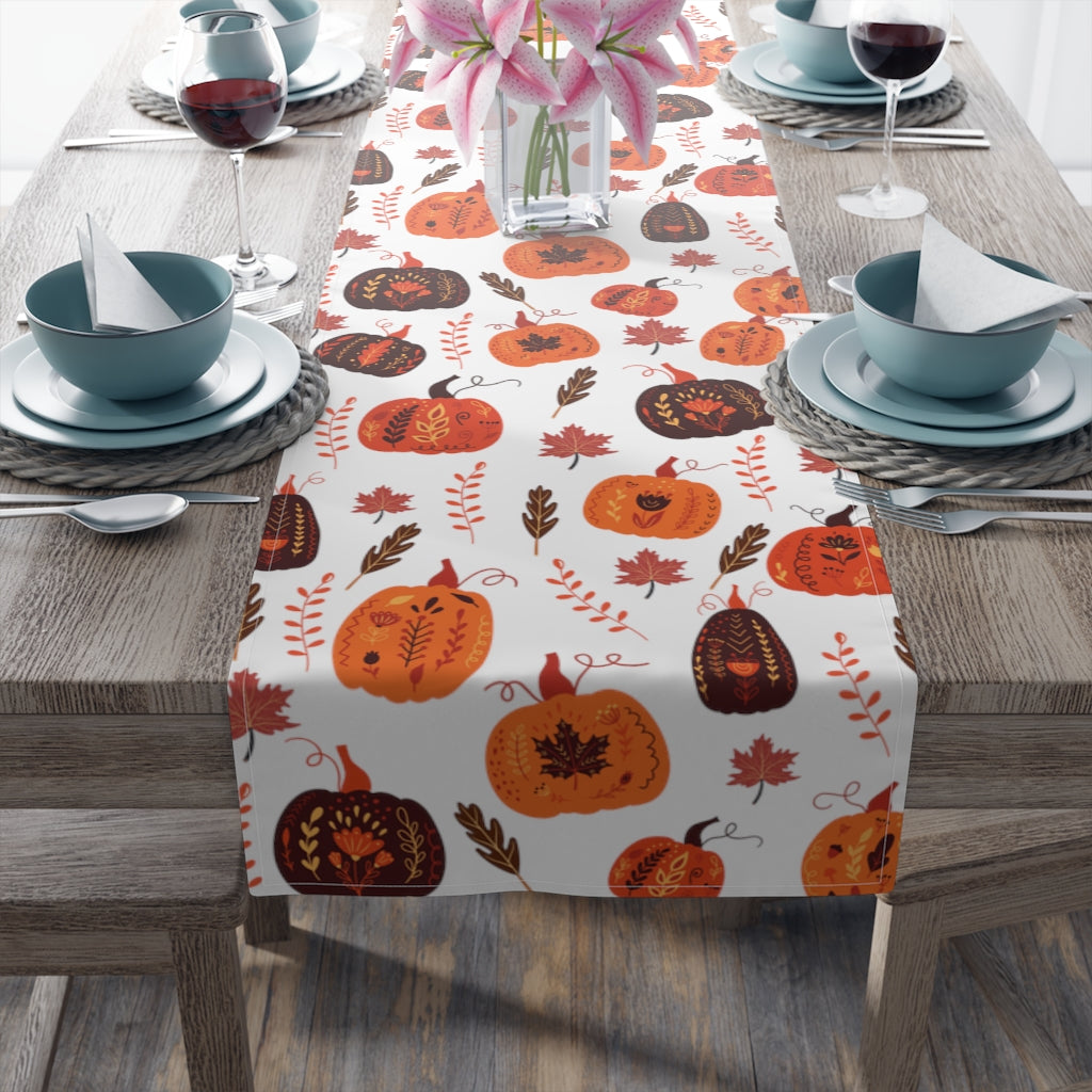 pumpkin table runner with orange and brown pumpkin pattern and fall leaves