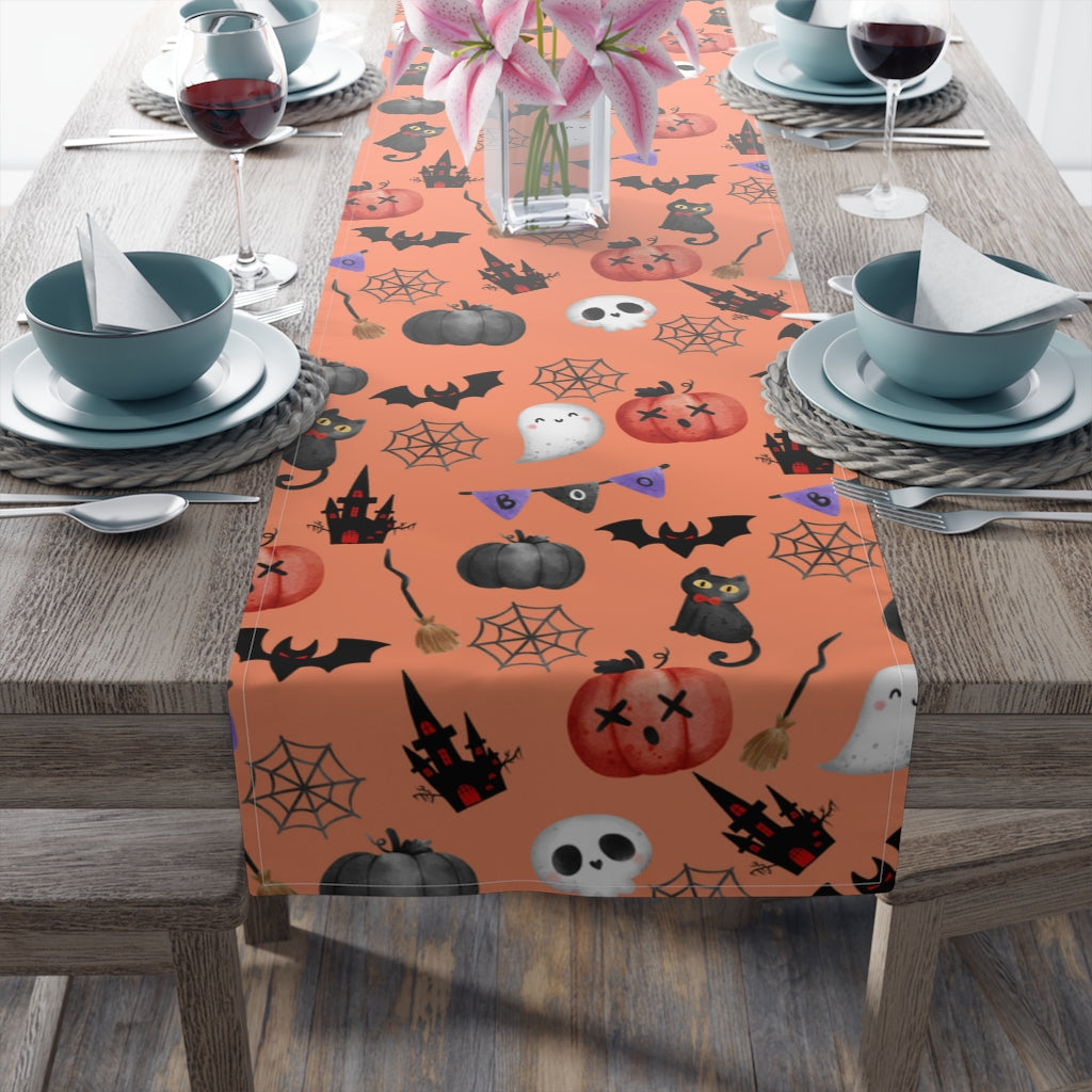 orange halloween table runner with pumpkin, spider, ghost, black cat, and skeleton pattern